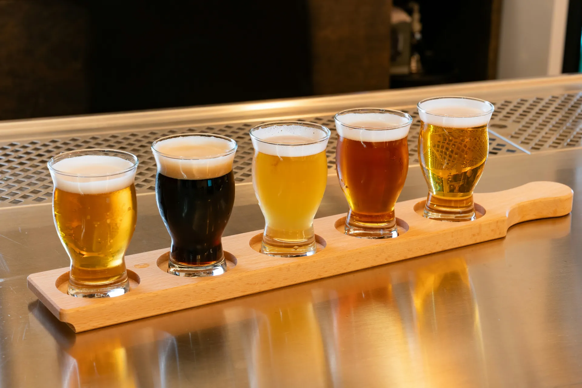 A flight of five craft beers on a wooden paddle at a bar